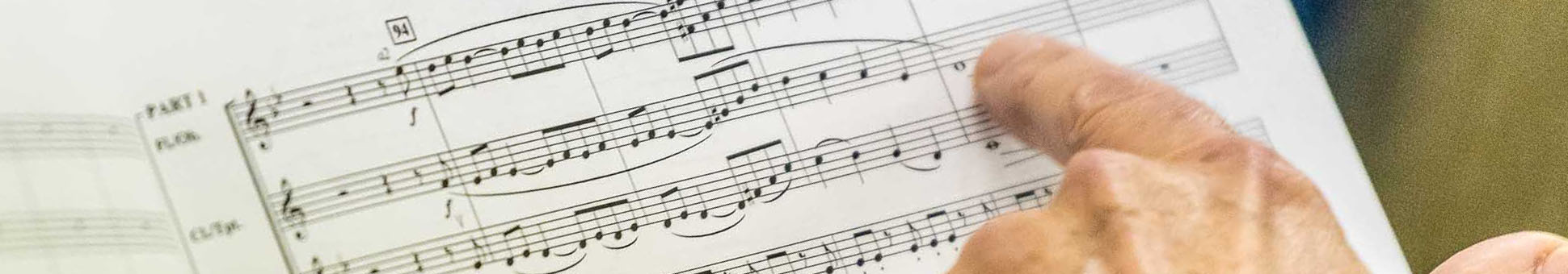 Hand einer Dirigentin zeigt auf eine Stelle im Notenblatt