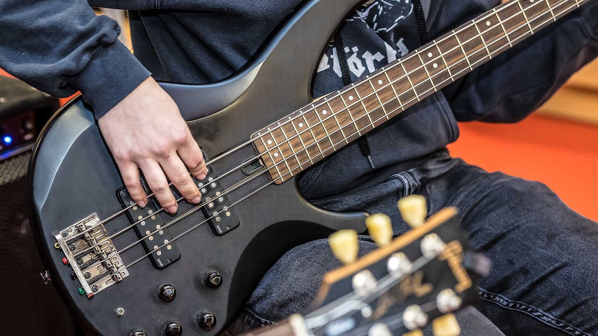 Jugendlicher spielt E-Bass; Detailfoto des Korpus