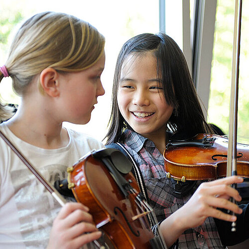 Drei Jugendliche üben Violine