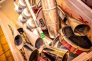 Kleinpercussion des Samba-Orchesters: Agogo, Tamborim, Chocalho, Ganza, liegen in einer Kiste