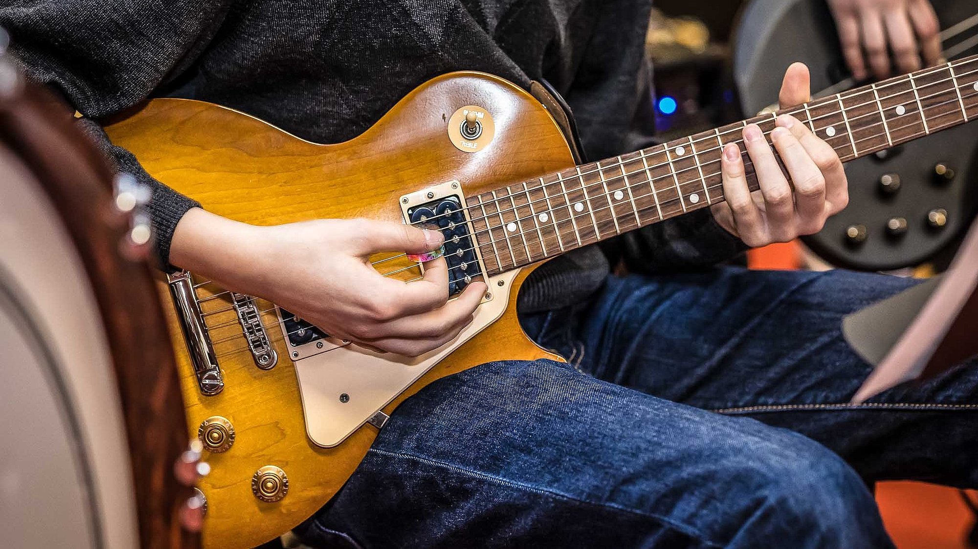 Jugendlicher spielt E-Gitarre; Detailfoto des Korpus