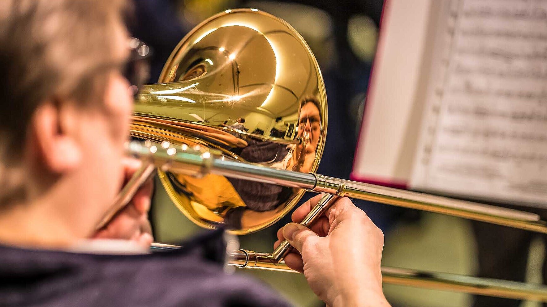 Nahaufnahme über die Schulter einer Posaunistin vor einem Notenblatt